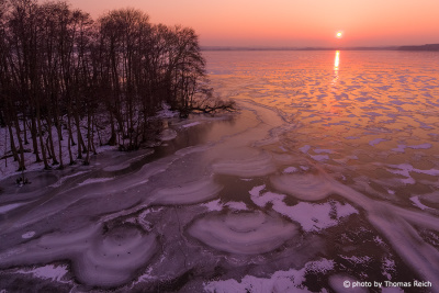 Sunset at the frozen Malchin Lake in winter