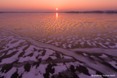 Sunset at the frozen Malchin Lake in winter from above