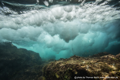 Underwater sea foam made by wave breaking seen from below water surface