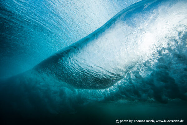 Underwater view of a wave with blue sky