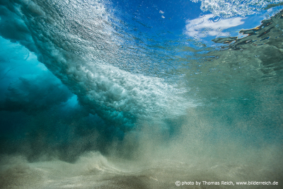 Underwater view of an ocean wave curling and splashing