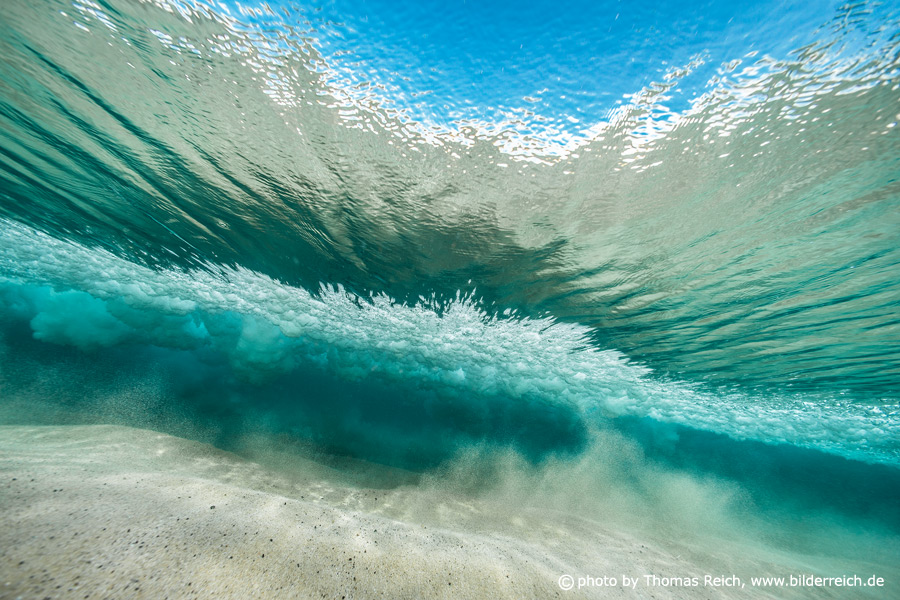 Underwater view of a wave with sunlight