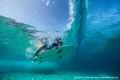 Surfer Girl drückt Surfbrett unter Wasser