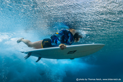 Surfer floating on surfboard underwater view