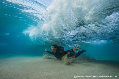 Female surfer diving below wave