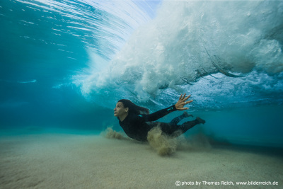 Surfer girl diving under wave
