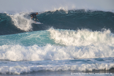 Männlicher Surfer auf einer blauen Welle