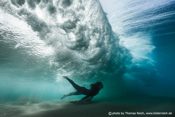 Beautiful girl diving beneath wave