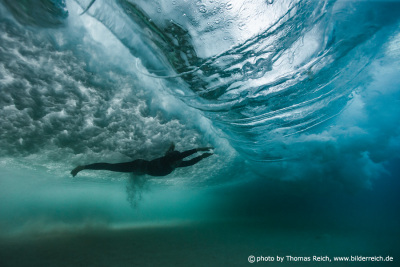 Girl diving beneath big vortex wave
