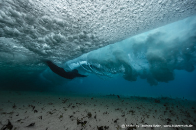 Frau taucht mit Meereswelle unter Wasser
