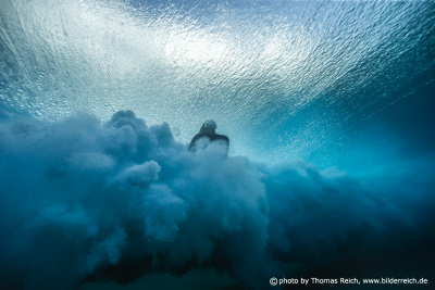 Surferin taucht unter Welle