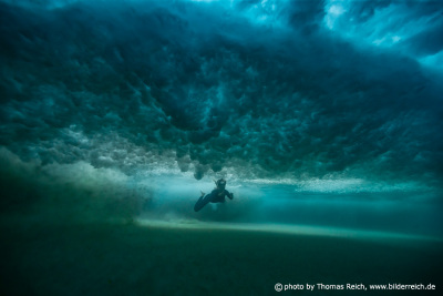 Woman diving beneath big vortex wave