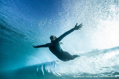 Sporty girl diving below wave