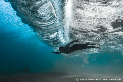 Woman diving below big breaking wave