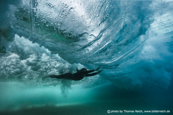 Girl diving with big ocean wave