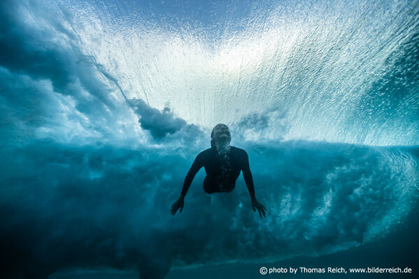 Surfer girl diving under big wave