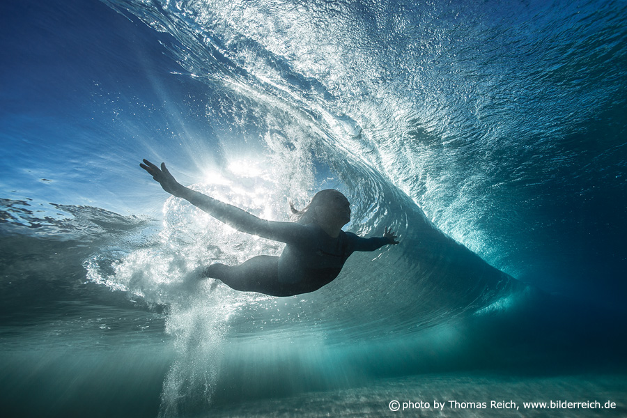 Beautiful woman diving beneath glassy wave